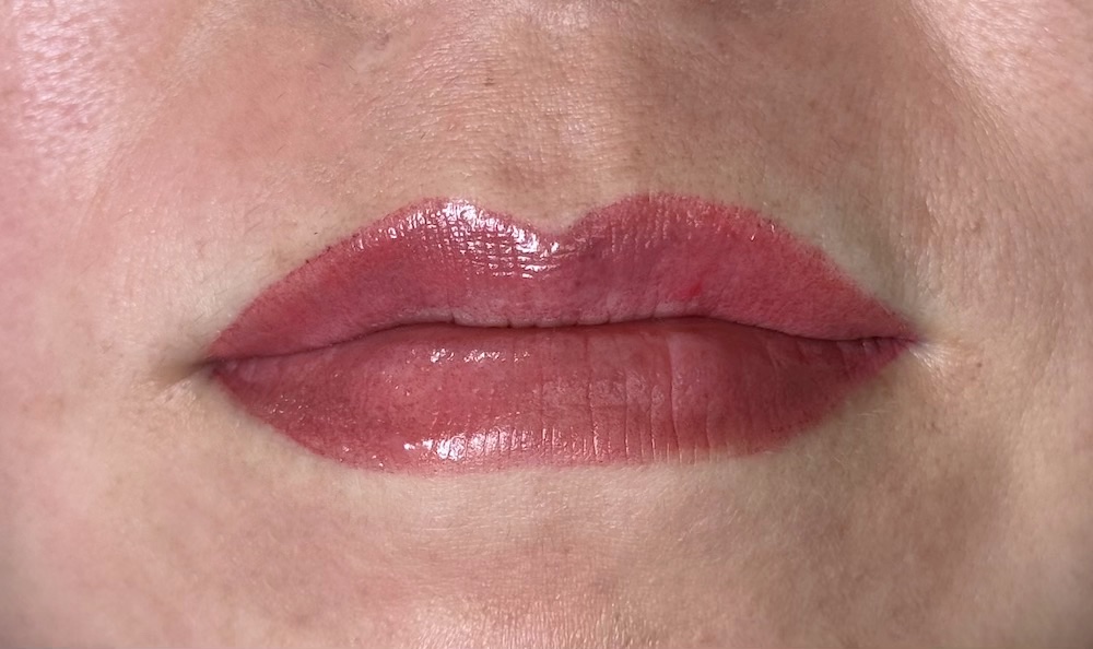 Close-up of fresh lip blush tattoo in a rosy pink-red shade