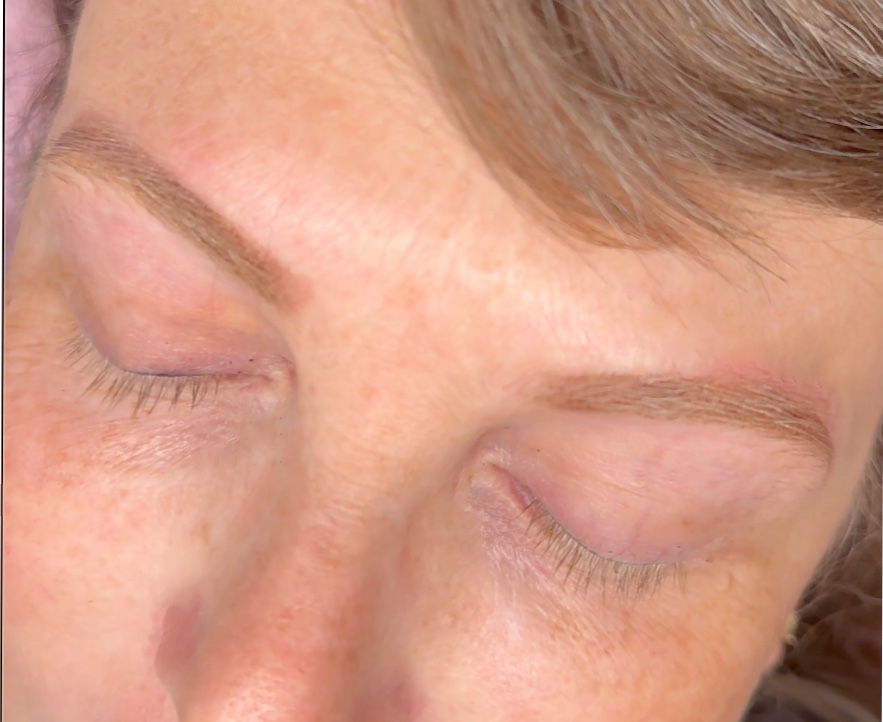 Close-up of fresh powder brow tattoo on closed eyelids